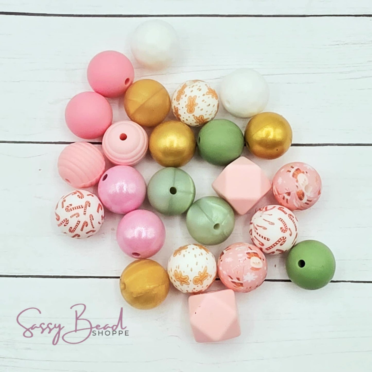 Close-up of Christmas-themed silicone beads in pink, sage, gold & white designs for DIY pens, badge reels, wristlets, cookie scribes, and all your jewelry making