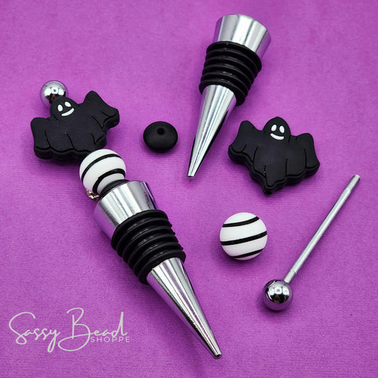 Halloween DIY kit styled flat lay showing beads for beaded wine stopper, including seasonal black ghost design