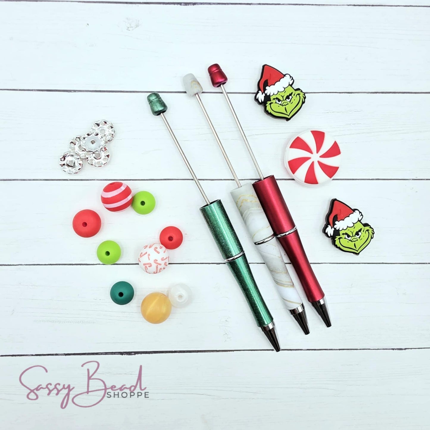 Christmas craft bead kit styled flat lay showing beads for beaded pens, including seasonal green guy and peppermint designs