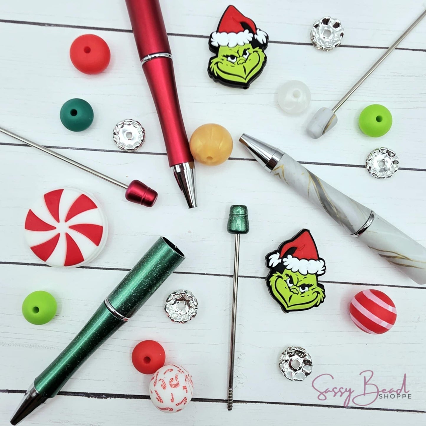 Close-up of Christmas-themed silicone beads in green guy and peppermint designs for DIY pen making