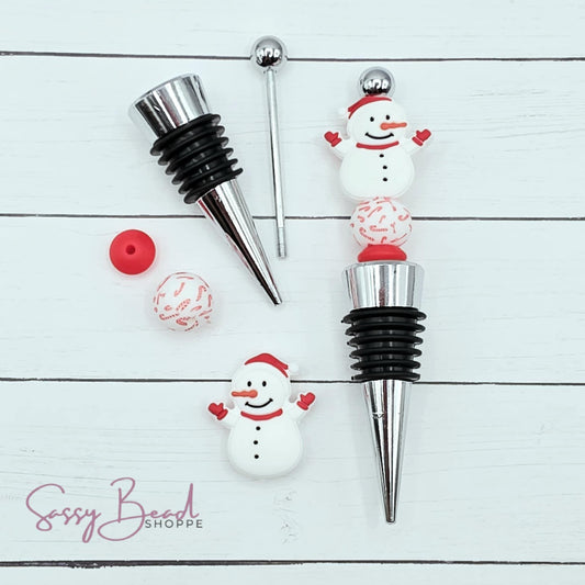 Close-up of Christmas-themed silicone beads in snowman and candy cane designs for DIY wine stopper making